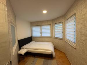 a small bedroom with a bed and two windows at Landmann City Ferienwohnung mit 6 Zimmern in Oberndorf am Neckar