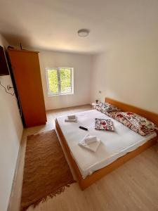 Un dormitorio con una cama grande con sábanas blancas y una ventana. en La Burlacu, en Eşelniţa