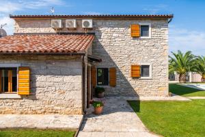 a stone house with orange shutters and a yard at Villa Orada for 6 people with private pool & only 2,5 km from the beach in Krnica