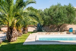 a swimming pool in a yard with palm trees at Villa Orada for 6 people with private pool & only 2,5 km from the beach in Krnica