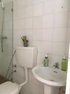 a white bathroom with a toilet and a sink at Alana's loft in Praia