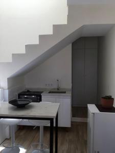 a white kitchen with a table and a staircase at Alana's loft in Praia