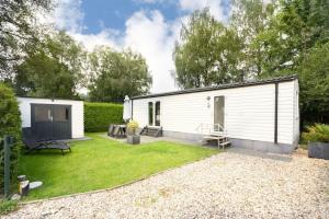 a small white building with a grass yard at Peaceful chalet with free parking and bikes in Putten