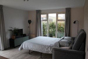 a bedroom with a bed and a chair and a window at Peaceful chalet with free parking and bikes in Putten +27 photos