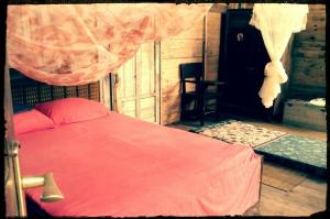 a bedroom with a bed with a red blanket at Sumatra Ecolodge in Sungaipisang