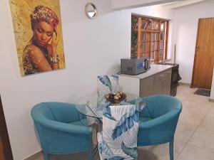 comedor con mesa de cristal y 2 sillas azules en Villa Theresa, en Johannesburgo