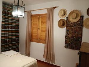 a bedroom with a window and straw hats on the wall at La Atalaya de Los Romanes in Viñuela