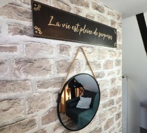 a mirror hanging on a brick wall with a chair at Les Apparts du Pont Vert - lit double - WiFi - tout inclus - 4 in Troyes