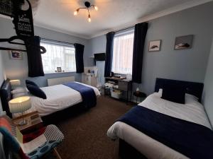 a bedroom with two beds and a chair in it at Westbrook Lodge Guest House in Margate