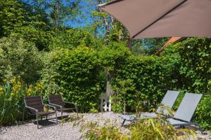 a group of chairs and an umbrella in a garden at Gîte du Rouard in Camiers