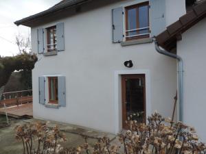 une maison blanche avec deux fenêtres et une porte dans l'établissement La Maison De Pierre, à La Chapelle-de-la-Tour