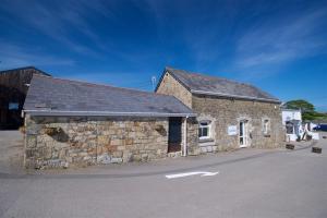a stone building with a black roof on a street at Eth Melyn Caravan Holiday in Grampound
