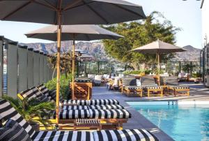 eine Gruppe von Liegestühlen und Sonnenschirmen neben einem Pool in der Unterkunft Rooftop Pool Modern 2BR, 2BA - Panoramic Hollywood views in Los Angeles