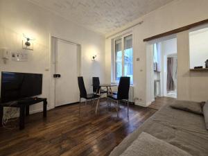 salon ze stołem, krzesłami i telewizorem w obiekcie Lisbonne - Bel appartement à Reims w mieście Reims