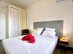 Una cama blanca con dos almohadas rojas. en Villa Charmante, Détente, Jacuzzi aux Avirons, en Les Avirons