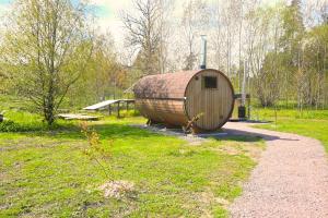 a large wooden barrel sitting in a grass field at Stuga Östensbo Gård in Österbybruk