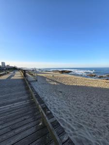 een strand met een houten pad naar de oceaan bij Cantinho Averomar in Póvoa de Varzim