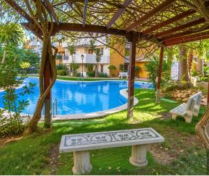 a bench under a pergola next to a swimming pool at Elegant Penthouse with Private Rooftop Punta Prima in Torrevieja +18 photos