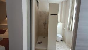 a white bathroom with a shower and a toilet at Hôtel L'Herbier d'Orange - Accueil Vélo in Orange