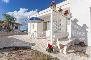 a white house with a bench and an umbrella at Villa Mirella - Salento Reservation in Racale