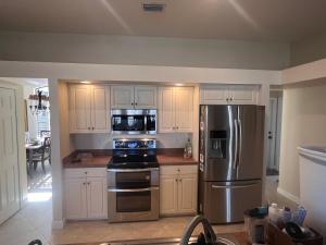 a kitchen with white cabinets and a stainless steel refrigerator at Imperial Paradise Naples in Bonita Springs