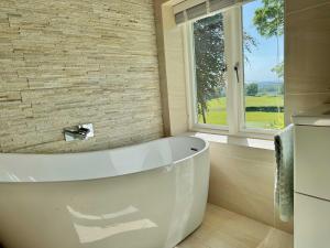 a white bath tub in a bathroom with a window at 2-Bed Cottage Garden Views near the Peak District in Macclesfield