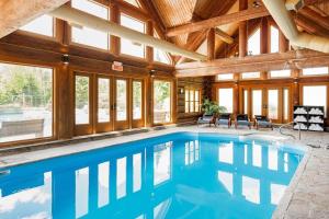 a swimming pool in a house with a wooden ceiling at Le Cerf 53 Fiddler Lake in Mille-Isles