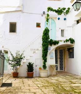 een wit gebouw met trappen en potplanten bij Casa L'Isule in Cisternino