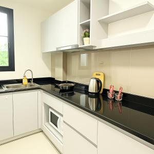 バンコクにあるZenith Place Huge 2BR Low-rise condoの白いキャビネットと黒いカウンタートップを備えたキッチン