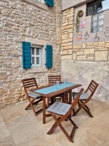 a wooden table and chairs with blue shutters at Akvamarin Stone House Istria in Medulin