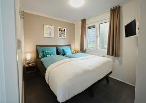 a bedroom with a bed with blue pillows and a window at Beachhouse Strandglück nur ca 100m bis zum Strand in Hulshorst