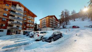 un parking avec des voitures garées dans la neige dans l'établissement Pracondu 2 001 - OUTDOOR & FUN charming apartment, à Nendaz