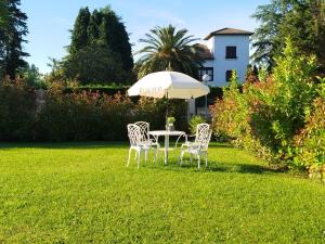 a table and chairs under an umbrella in a yard at Cabárceno Chalet vacacional Casa Pedro La Abadilla in La Abadilla
