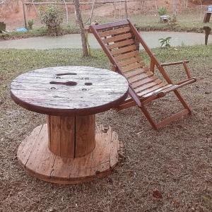 a wooden table and a chair sitting on top of a tree stump at Camping e pousada dos sonhos in Carvalhos