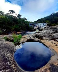a pool of water on the rocks with a waterfall at Camping e pousada dos sonhos in Carvalhos