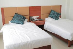 a hotel room with two beds and a night stand at Z.H.P Hotel in Ban Khlong Nung