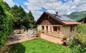 a house with a deck with chairs and a table at le home du Morel et son jacuzzi in Bellecombe