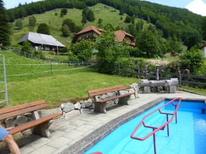 a person standing next to a swimming pool with benches at Haus am Rotwiesenbach in Todtnau