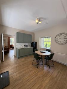 a kitchen with a table and a clock on the wall at Drumlinn Cottage in Bridge of Cally