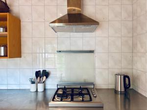 a stove top oven in a kitchen with a hood at Boutique tent 'Pruum' op een unieke plek in het groen met luxe bed in Vorden