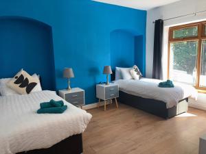 a blue bedroom with two beds and a window at Welbeck House, close to Swansea Central in Cockett
