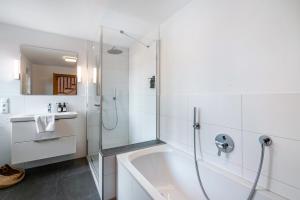 a white bathroom with a tub and a shower at Haus Kreiznegge in Inzell +17 photos