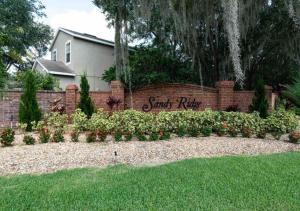 einen Steinzaun mit einem Schild im Garten in der Unterkunft 5 bedroom, 7 bed , 3 bathroom Midterm Rental Home with Pool and Game room, near Disney in Davenport