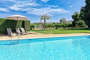 a swimming pool with two chairs and an umbrella at Orange Grove Villa in Nafplio