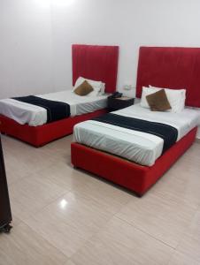 two beds with red frames in a room at Hotel Tulip Inn, Gulberg in Lahore