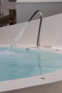 a fountain in a bath tub with blue water at Byzantio Beach Suites & Wellness in Agios Sostis