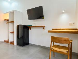 ein Zimmer mit einem schwarzen Kühlschrank und einem Holzstuhl in der Unterkunft Kanchana Cottages in Uluwatu