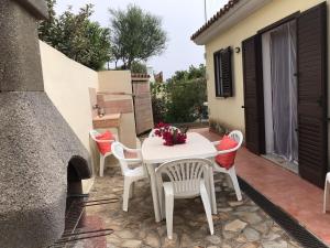 a white table and chairs on a patio with a fireplace at AffittaSardegna - Casa delle Dune in Capo Comino