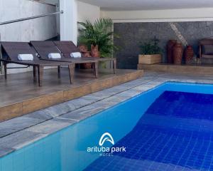 a pool with a table and chairs next to a house at Arituba Park Hotel in Natal