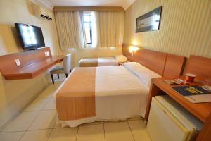 a hotel room with two beds and a desk at Arituba Park Hotel in Natal